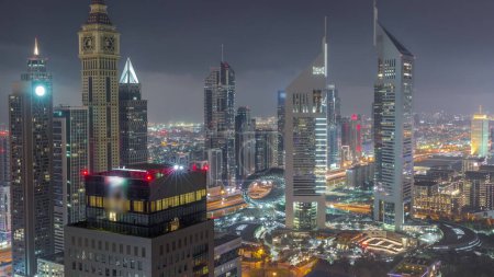Foto de Los rascacielos en Sheikh Zayed Road y DIFC duran toda la noche en Dubái, Emiratos Árabes Unidos. Torres en el centro financiero vista aérea desde arriba con luces apagadas - Imagen libre de derechos