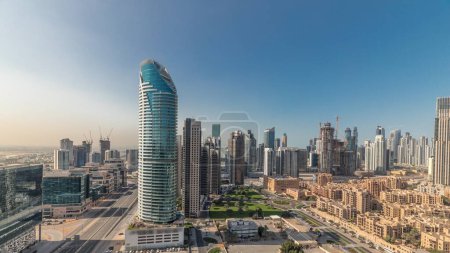 Téléchargez les photos : Panorama montrant la baie d'affaires et les tours du centre-ville de Dubaï timelapse du matin aérien. Vue sur le toit de certains gratte-ciels et de nouveaux bâtiments en construction avec des maisons thaditionnelles du vieux quartier de la ville - en image libre de droit