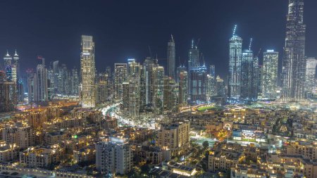 Téléchargez les photos : Futuriste paysage urbain nocturne aérien timelapse avec l'architecture illuminée du centre-ville de Dubaï. De nombreux gratte-ciel et tours illuminés. Le quartier de la vieille ville. Émirats arabes unis. - en image libre de droit
