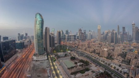 Téléchargez les photos : Panorama des tours de la baie d'affaires de Dubaï, de nuit aérienne au jour, période de transition. Vue sur le toit de certains gratte-ciel et de nouveaux bâtiments en construction avant le lever du soleil - en image libre de droit