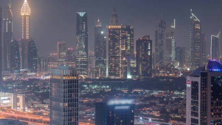 Foto de Filas de rascacielos en el distrito financiero de Dubai día aéreo a noche timelapse transición. Vista panorámica de muchas torres desde el distrito de Business Bay - Imagen libre de derechos