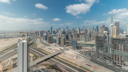 Foto de Panorama que muestra el horizonte de Dubai con la bahía de negocios y el timelapse del centro de distrito. Vista aérea de muchos rascacielos modernos con cielo azul nublado. Emiratos Árabes Unidos. - Imagen libre de derechos
