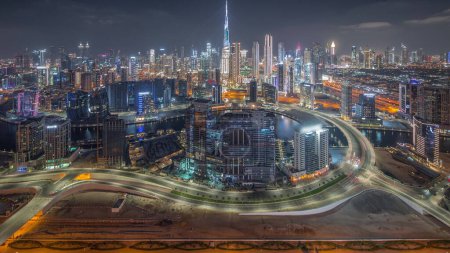 Foto de Skyline panorámico de Dubai con sitio de construcción de la bahía de negocios y timelapse de noche del distrito centro. Vista aérea de muchos rascacielos modernos y tráfico ocupado en la carretera al khail. Emiratos Árabes Unidos. - Imagen libre de derechos