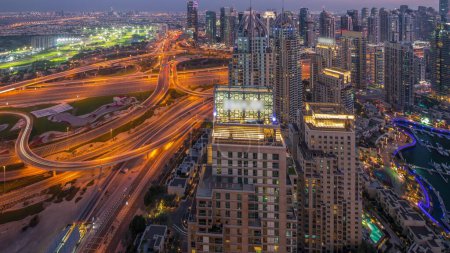 Foto de Dubai marina y los rascacielos JLT a lo largo de Sheikh Zayed carretera aérea día a noche timelapse transición. Edificios residenciales y de oficinas desde arriba con gran encrucijada - Imagen libre de derechos