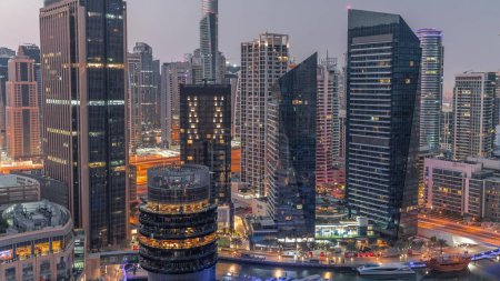 Photo for Dubai Marina Skyline with JLT district skyscrapers on a background aerial night to day transition timelapse. Illuminated towers with glass surface before sunrise - Royalty Free Image