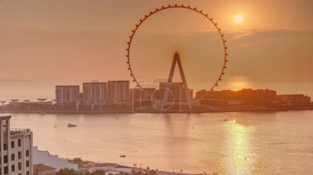 Photo for Sunset over Bluewaters island with modern architecture and ferris wheel aerial timelapse. New leisure and residential area near Dubai marina and JBR. Orange sky - Royalty Free Image