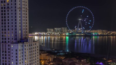 Photo for Bluewaters island with modern architecture and ferris wheel aerial during all night timelapse with lights turning off. New leisure and residential area near Dubai marina and JBR - Royalty Free Image