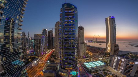 Foto de Panorama de la zona de Dubai Marina y JBR y el famoso puente aéreo Ferris Wheel de día a noche. Playas de arena dorada en el Golfo Pérsico después del atardecer - Imagen libre de derechos