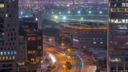 Téléchargez les photos : Vue panoramique de la circulation sur la rue Al Saada près de la nuit du quartier DIFC et du quartier Deira sur un fond avant le lever du soleil à Dubaï, Émirats arabes unis. Gratte-ciels dans la place financière aérienne d'en haut. Fenêtres éclatantes - en image libre de droit