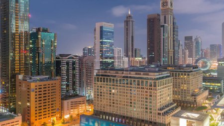 Foto de Dubai International Distrito financiero noche a día timelapse transición. Vista aérea de las torres de oficinas de negocios antes del amanecer. Rascacielos iluminados con hoteles cerca del centro - Imagen libre de derechos