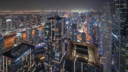 Photo for Panorama showing Dubai Marina with JLT and JBR district. Traffic on highway between skyscrapers aerial night timelapse. Illuminated modern towers and construction site - Royalty Free Image