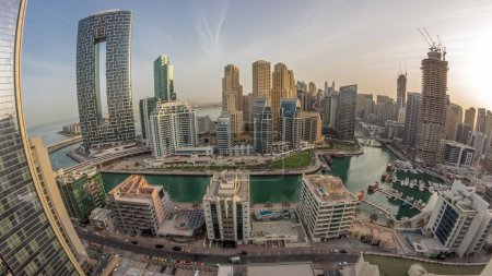 Foto de Panorama de Dubai Marina con barcos y yates aparcados en el puerto y rascacielos alrededor del canal de la mañana timelapse aérea durante la salida del sol. Torres del distrito JBR en segundo plano - Imagen libre de derechos