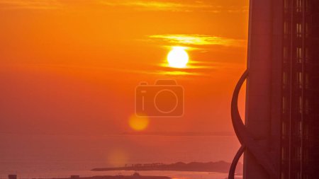 Photo for Sunset over sea near Dubai water canal with orange sky aerial timelapse. View from above behind skyscraper - Royalty Free Image