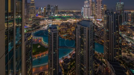 Foto de Vista aérea de una gran ciudad futurista con noche de lago y fuentes. Bahía de negocios y distrito centro con muchos rascacielos y casas tradicionales, Dubai, Emiratos Árabes Unidos skyline. - Imagen libre de derechos