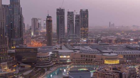 Téléchargez les photos : Dubaï centre-ville avec fontaines et architecture futuriste moderne nuit aérienne à la transition quotidienne timelapse. Vue sur les gratte-ciel avec quartier financier et centre commercial - en image libre de droit