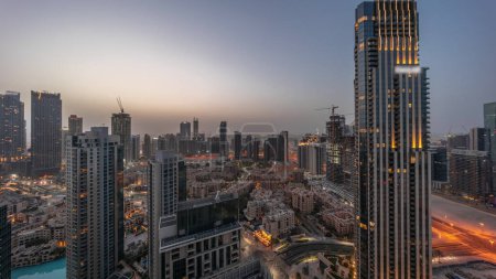Foto de Vista panorámica aérea de una gran transición futurista noche a día. Bahía de negocios y distrito Downtown antes del amanecer con rascacielos y casas tradicionales, Dubai, Emiratos Árabes Unidos skyline. - Imagen libre de derechos