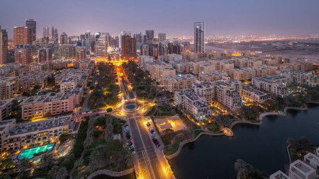 Téléchargez les photos : Des gratte-ciel dans le quartier de Barsha Heights et des immeubles de faible hauteur dans le quartier des Verts se succèdent de jour comme de nuit. Dubai skyline avec palmiers et zone de marche nead étang - en image libre de droit