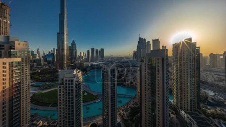 Photo for Dubai Downtown cityscape during sunrise with reflections from tallest skyscrapers aerial timelapse. Sun rising behind towers. Busy roads with traffic from above - Royalty Free Image