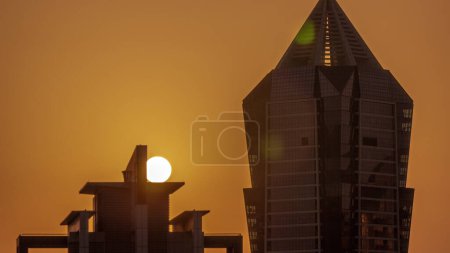 Foto de Puesta de sol sobre torres modernas desarrollo residencial en Business Bay timelapse aéreo, Dubai, Emiratos Árabes Unidos. Rascacielos con cielo naranja por la noche - Imagen libre de derechos