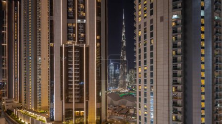Photo for Panorama showing tallest skyscrapers during Earth hour in downtown dubai located on bouleward street near shopping mall aerial night timelapse. Lights and illumination turning on after one hour - Royalty Free Image