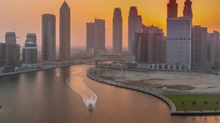 Foto de Paisaje urbano al atardecer de rascacielos en Dubai Business Bay con timelapse aéreo del canal de agua. skyline moderno con torres y paseo marítimo. Un centro de negocios internacionales - Imagen libre de derechos