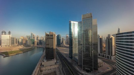 Photo for Cityscape with sun reflected from skyscrapers of Dubai Business Bay during sunrise with water canal aerial timelapse. Modern skyline with towers and waterfront. A center of international business - Royalty Free Image