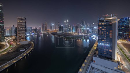 Foto de Panorama que muestra el paisaje urbano de los rascacielos en Dubai Business Bay con el canal de agua de la noche aérea timelapse. skyline moderno con torres iluminadas y paseo marítimo. Un centro de negocios internacionales - Imagen libre de derechos