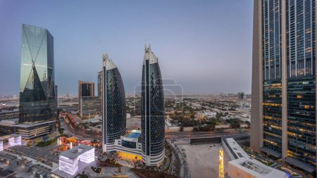 Foto de Vista aérea del Distrito Financiero Internacional de Dubái con muchos rascacielos panorámicos nocturnos después del atardecer. Tráfico en carreteras cerca de la avenida comercial con zona de paseo en la azotea. Dubai, Emiratos Árabes Unidos. - Imagen libre de derechos