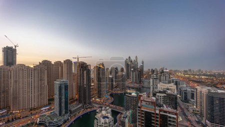Photo for Panorama of various skyscrapers in tallest recidential block in Dubai Marina aerial day to night transition timelapse with artificial canal. Many towers in JBR district and yachts after sunset - Royalty Free Image