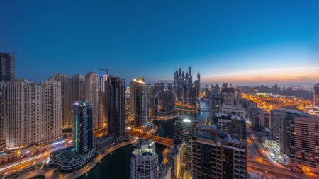 Foto de Panorama de varios rascacielos en el bloque recidencial más alto de Dubai Marina aéreo noche al día timelapse transición con canal artificial. Muchas torres en el distrito JBR y yates antes del amanecer - Imagen libre de derechos