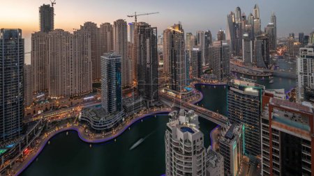 Photo for View of various skyscrapers in tallest recidential block in Dubai Marina and JBR district aerial day to night transition timelapse with artificial canal. Many towers and yachts after sunset - Royalty Free Image