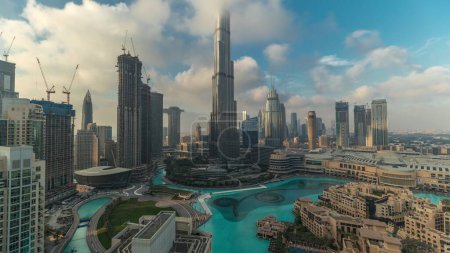 Téléchargez les photos : Gratte-ciel s'élevant au-dessus du centre-ville de Dubaï, centre commercial et fontaine entourés de bâtiments modernes vue panoramique aérienne avec ciel nuageux - en image libre de droit