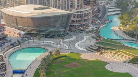 Téléchargez les photos : L'Opéra de Dubaï situé au centre-ville est le centre radieux de la culture et des arts de Dubaï. Lac artificiel et parc avec palmiers vue aérienne du soir d'en haut - en image libre de droit