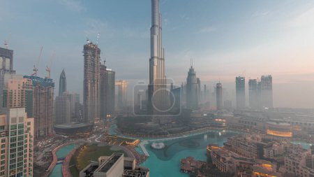 Téléchargez les photos : Aerial view of Dubai city early morning during fog night to day transition . Futuristic city panoramic skyline with skyscrapers and towers from above - en image libre de droit