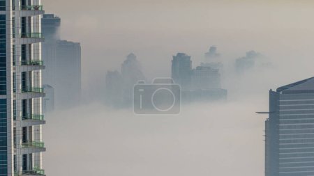 Photo for Dubai Aerial view showing fog over al barsha heights and greens district area  from Dubai marina. Towers and skyscrapers foggy morning from above - Royalty Free Image
