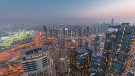 Téléchargez les photos : Panorama of Dubai Marina with JLT skyscrapers day to night transition , Dubai, United Arab Emirates. Aerial view from above towers after sunset with traffic on highway - en image libre de droit