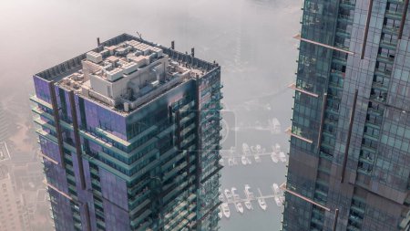 Foto de Top view with modern skyscrapers aerial  and water pier of Dubai Marina with morning haze, United Arab Emirates. Yachts and boats between glass towers - Imagen libre de derechos