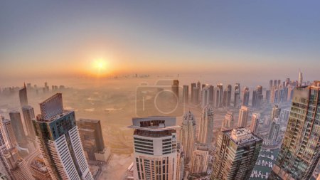 Téléchargez les photos : Panorama of Dubai Marina with JLT skyscrapers and golf course during sunrise , Dubai, United Arab Emirates. Aerial view from above towers foggy morning. City skyline with rooftops - en image libre de droit