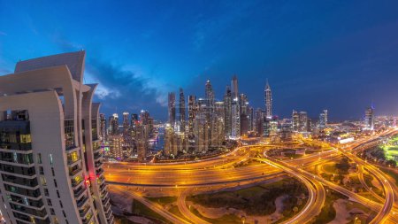 Foto de Panorama of Dubai Marina after sunset highway intersection spaghetti junction day to night transition . Illuminated tallest skyscrapers on a background. Aerial top view from JLT district. - Imagen libre de derechos