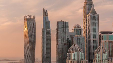 Foto de Rascacielos de Dubai Marina con los edificios residenciales más altos durante la puesta del sol con el sol reflejado desde una superficie de vidrio. Vista aérea desde el distrito JLT - Imagen libre de derechos