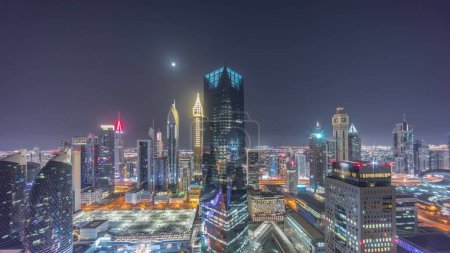 Photo for Panorama of futuristic skyscrapers in financial district business center in Dubai on Sheikh Zayed road during all night . Aerial view from above with illuminated towers and moon - Royalty Free Image