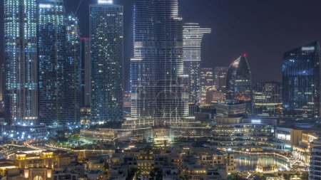 Téléchargez les photos : Dubaï Centre-ville toute la nuit avec le plus haut gratte-ciel et d'autres tours éclairées avec des lumières éteignant vue du haut, Émirats arabes unis. Maisons traditionnelles de la vieille ville avec centre commercial - en image libre de droit