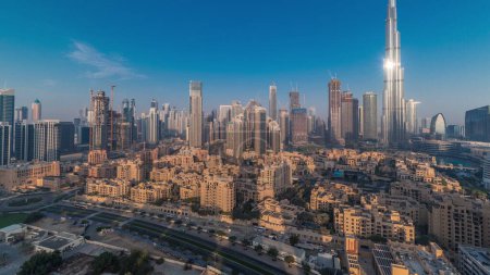 Photo for Dubai Downtown morning panorama with sun reflected from tallest skyscraper and other towers view from the top during sunrise with long shadows, United Arab Emirates. Traditional houses of old town - Royalty Free Image