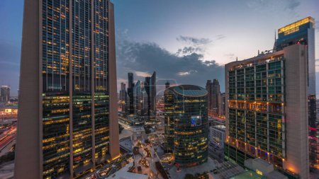 Photo for Dubai international financial center skyscrapers aerial day to night transition . Illuminated towers with promenade panoramic view from above after sunset - Royalty Free Image
