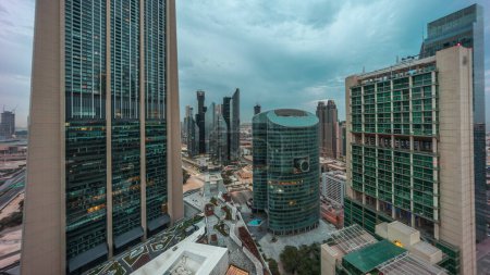 Photo for Dubai international financial center skyscrapers panorama aerial night to day transition . Illuminated towers view from above before sunrise with cloudy colorful sky - Royalty Free Image