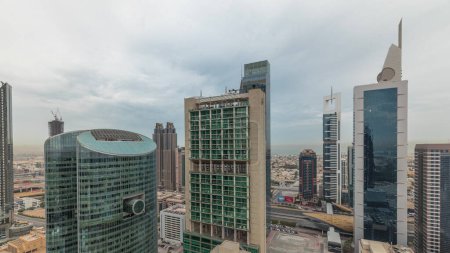 Foto de Panorama showing Dubai international financial center skyscrapers with promenade on a gate avenue aerial . Many office towers and traffic on a highway. Cloudy sky - Imagen libre de derechos