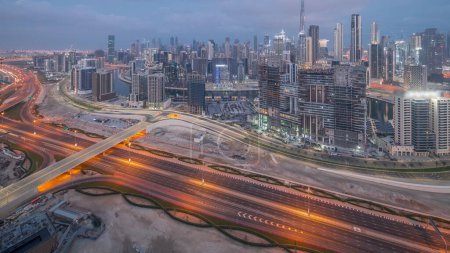 Foto de Skyline panorámico Dubai con la bahía de negocios y el centro de la noche de distrito con el tráfico en al khail carretera. Vista aérea de muchos rascacielos modernos y obras de construcción antes del amanecer. Emiratos Árabes Unidos - Imagen libre de derechos