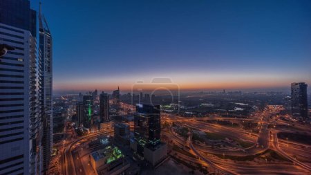 Foto de Aerial panoramic view of media city and al barsha heights district with golf course night to day transition  from Dubai marina. Towers and skyscrapers with traffic on a highway intersection from above - Imagen libre de derechos