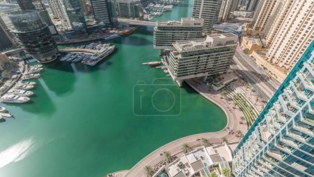 Téléchargez les photos : Vue aérienne vers le bas des gratte-ciel de la marina de Dubaï autour du canal avec des bateaux flottants avec des ombres se déplaçant rapidement. Bateaux blancs sont garés dans le yacht club et à proximité du centre commercial - en image libre de droit