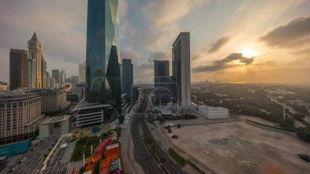 Foto de Sunrise in Dubai International Financial district transition . Panoramic aerial view of business office towers at morning. Skyscrapers with hotels and shopping malls near downtown - Imagen libre de derechos